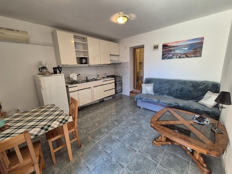 Otwarty salon z kuchnią, stołem jadalnym i sofą, wyposażony w podłogi wyłożone kafelkami.