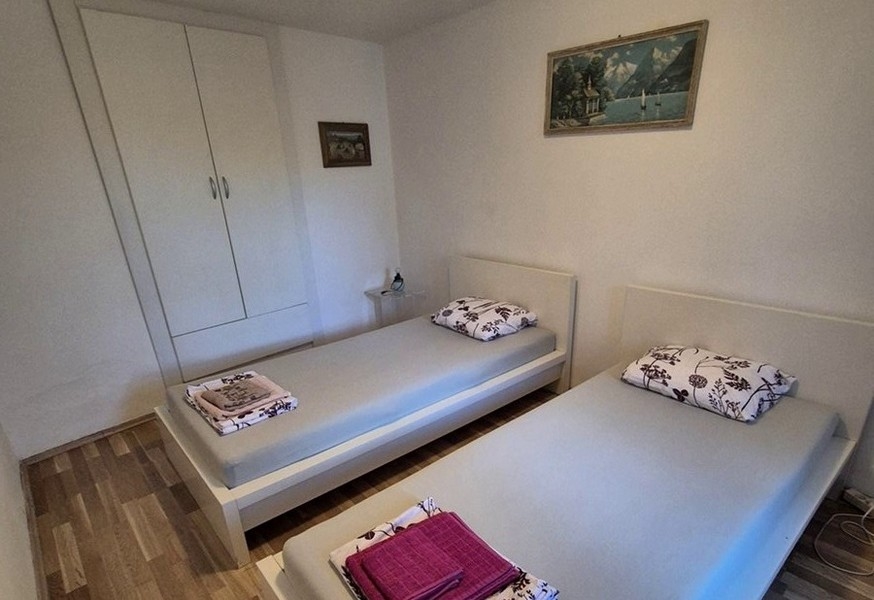 Sypialnia z dwoma pojedynczymi łóżkami i prostymi meblami.