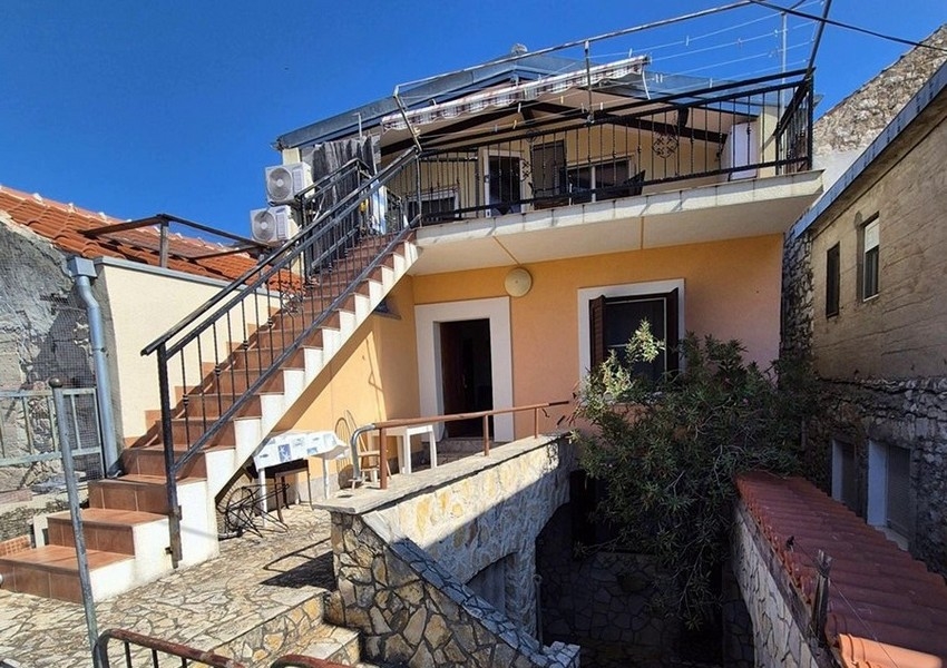 Widok z tyłu śródziemnomorskiego kamiennego domu z zewnętrznymi schodami i tarasem.