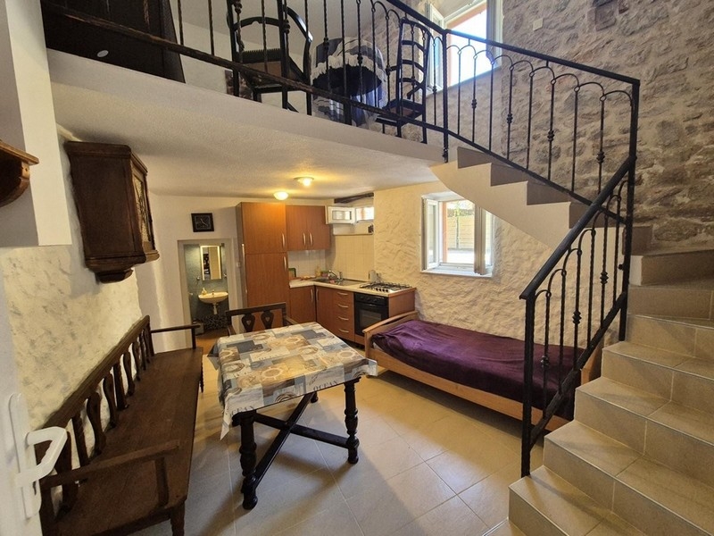 Część dzienna w stylu rustykalnym z drewnianymi belkami i kamiennymi schodami.