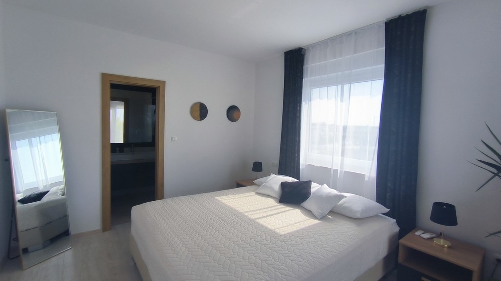 Druga sypialnia z dużym łóżkiem i przylegającą łazienką.