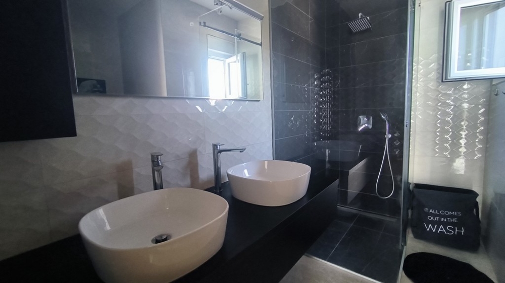 Nowoczesna łazienka z podwójną umywalką i prysznicem ze strumieniem deszczowym.