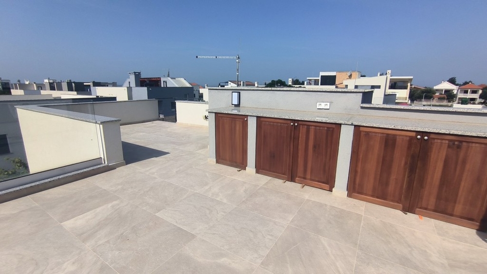 Przestronny taras na dachu z wbudowanymi drewnianymi meblami.