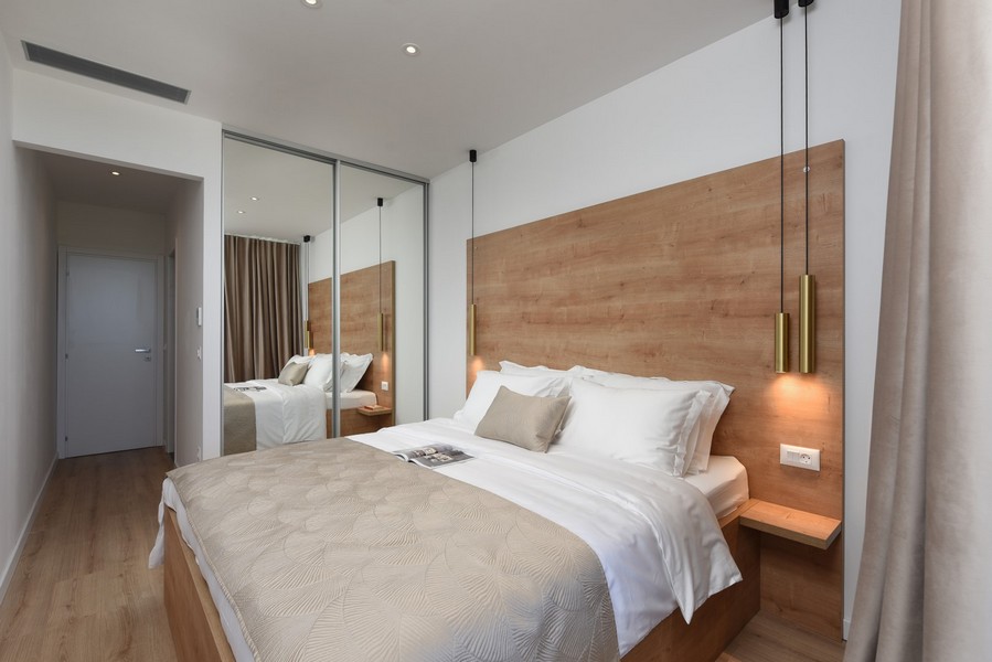 Przytulna sypialnia z drewnianymi dekoracjami, szafką z lustrem i bezpośrednim wyjściem na balkon.