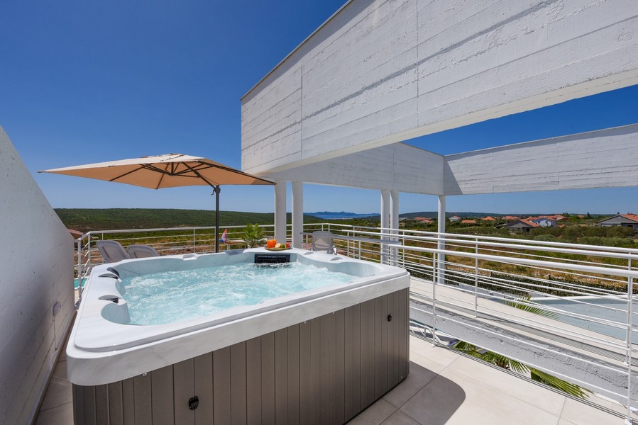 Wanna z hydromasażem na świeżym powietrzu na górnym tarasie z widokiem na okolicę i morze.