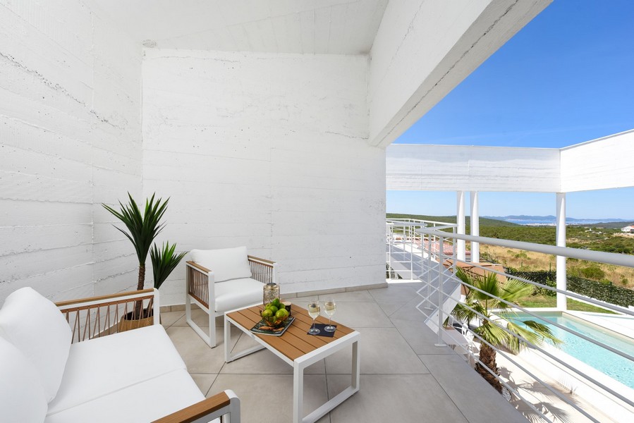 Zadaszony taras z częścią wypoczynkową i widokiem na basen i okolicę.