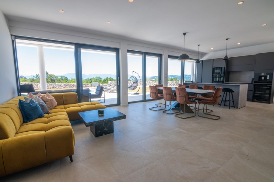 Część dzienna z żółtą sofą, jadalnią i otwartą kuchnią, panoramiczne okno