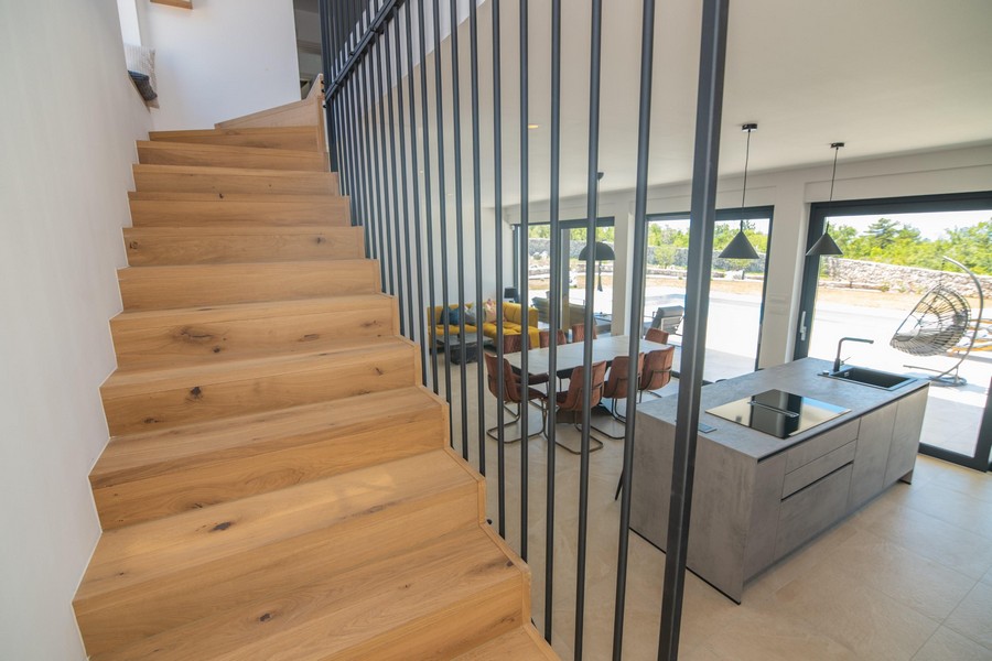Schody drewniane z metalową poręczą, widok na część dzienną