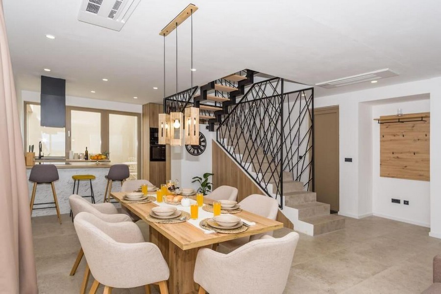 Widok na stół jadalny i kuchnię oraz nowoczesną klatkę schodową willi.