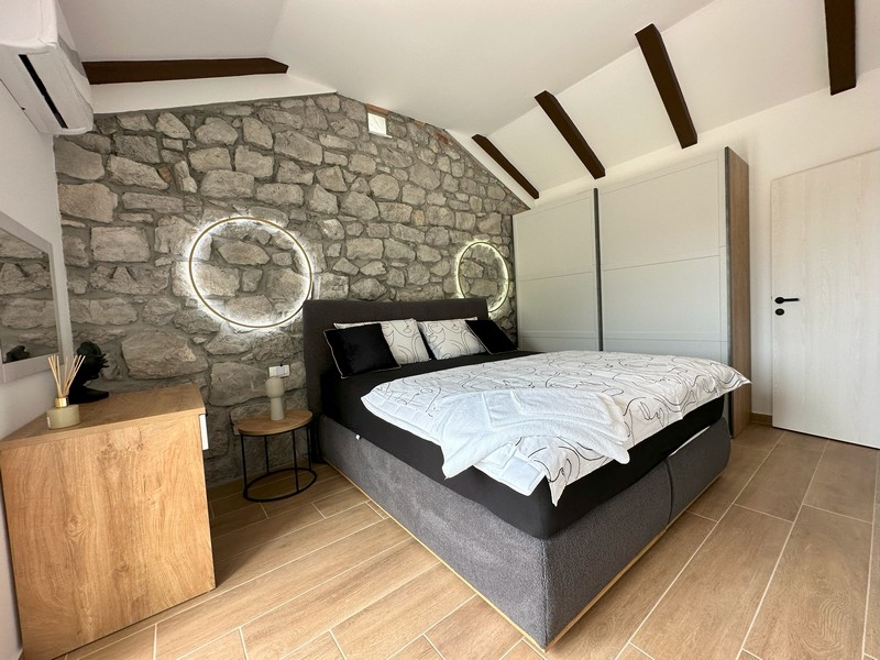 Sypialnia z kamienną ścianą i nowoczesnymi akcentami