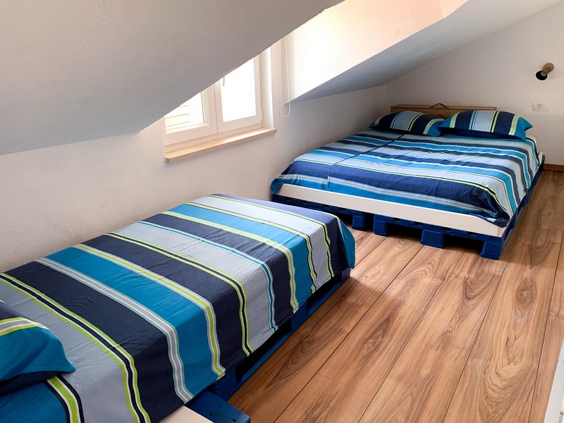 Sypialnia na poddaszu z łóżkiem podwójnym i łóżkiem pojedynczym