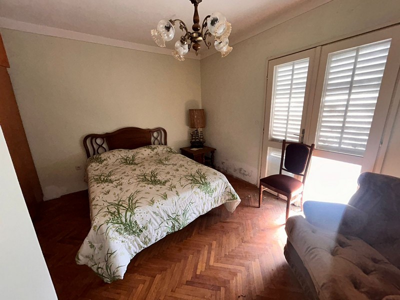 Sypialnia z podwójnym łóżkiem, jasnym oknem i starymi meblami