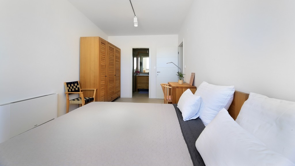 Widok z żywopłotu na basen i część wypoczynkową z wejściem do willi.