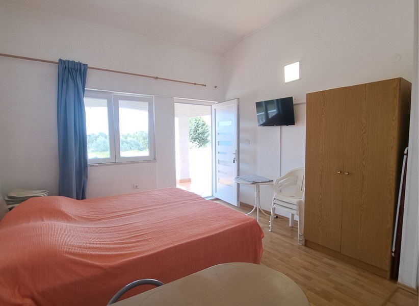 Sypialnia z łóżkiem, TV i wyjściem na taras.