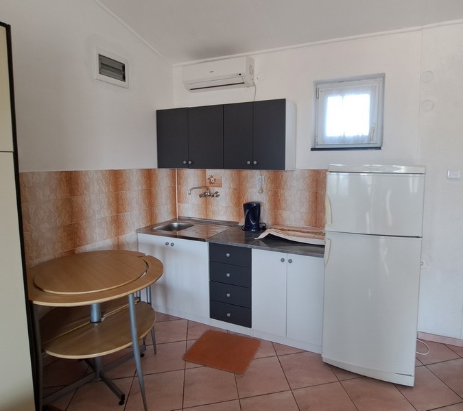 Aneks kuchenny z małym stołem i lodówką.