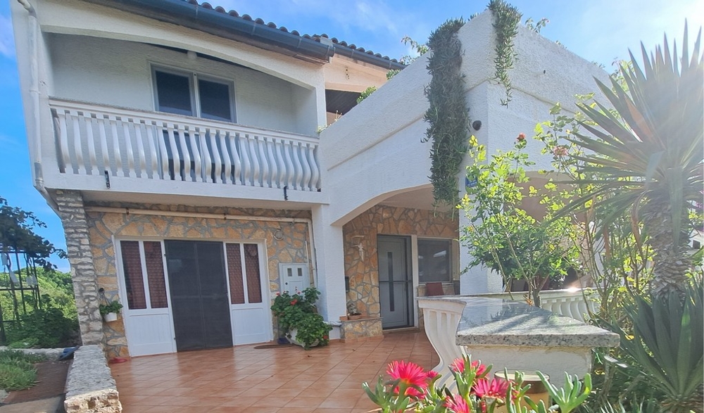 Widok z przodu domu z balkonem i ogrodem.