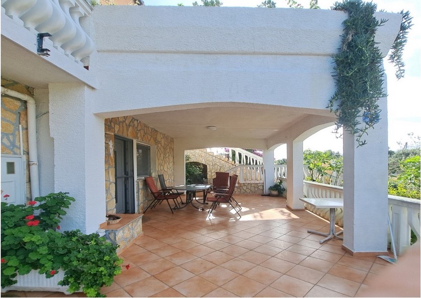 Zadaszony taras z miejscami do siedzenia i roślinami.