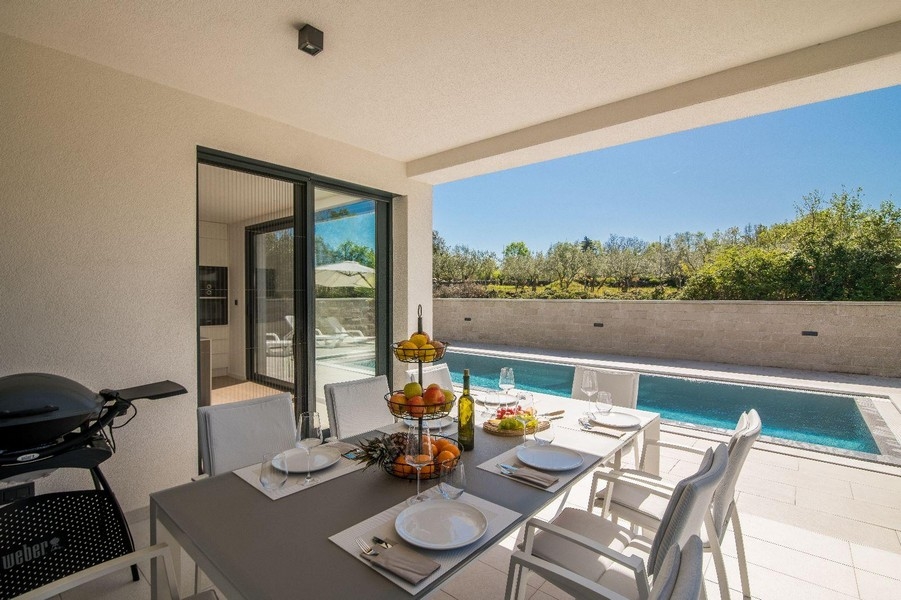 Zadaszony taras ze stołem jadalnym i widokiem na basen