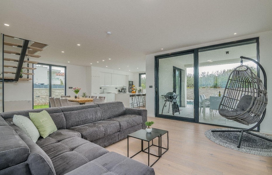 Otwarta część dzienna z sofą, wiszącym krzesłem i kuchnią