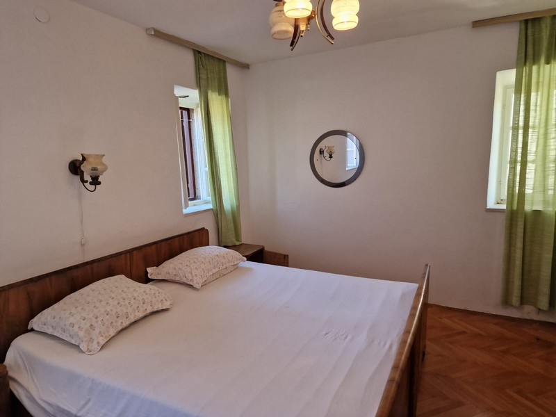 Sypialnia z podwójnym łóżkiem, drewnianą ramą i zielonymi zasłonami