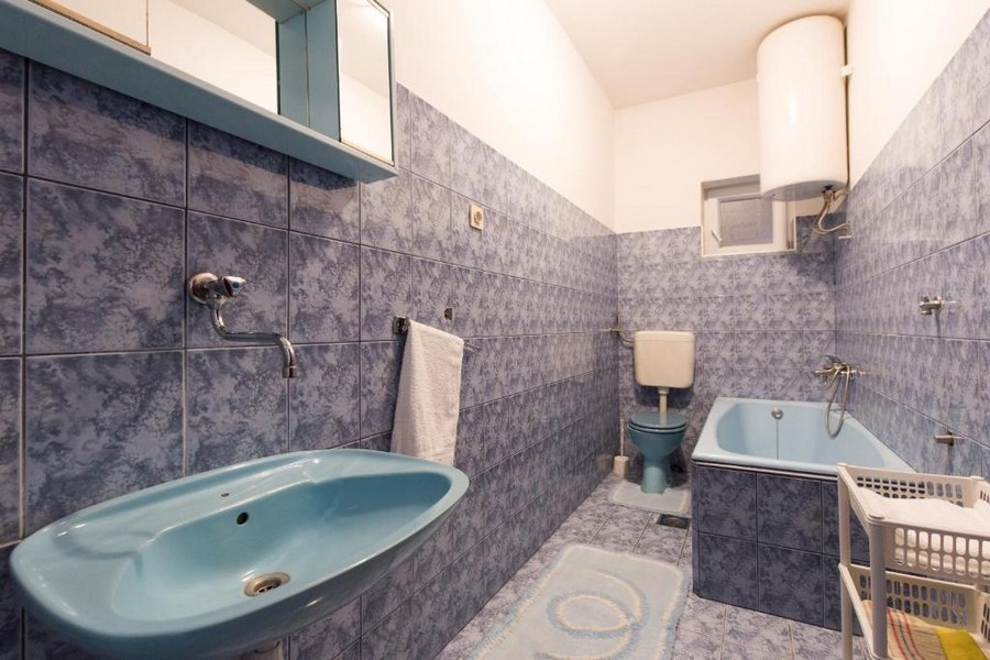 Łazienka z niebieskimi płytkami, wanną i umywalką