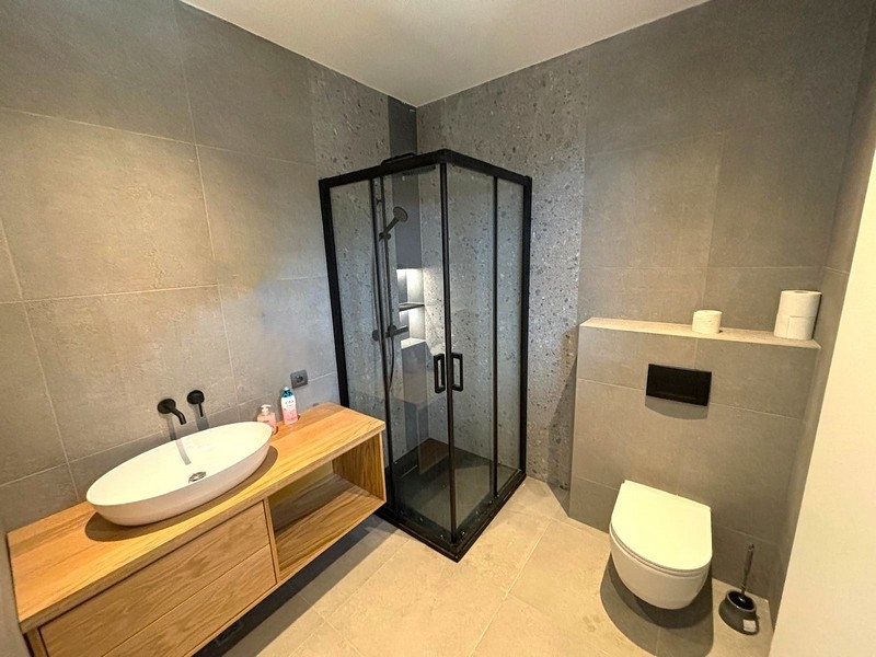 Nowoczesna łazienka ze szklanym prysznicem i drewnianą toaletką