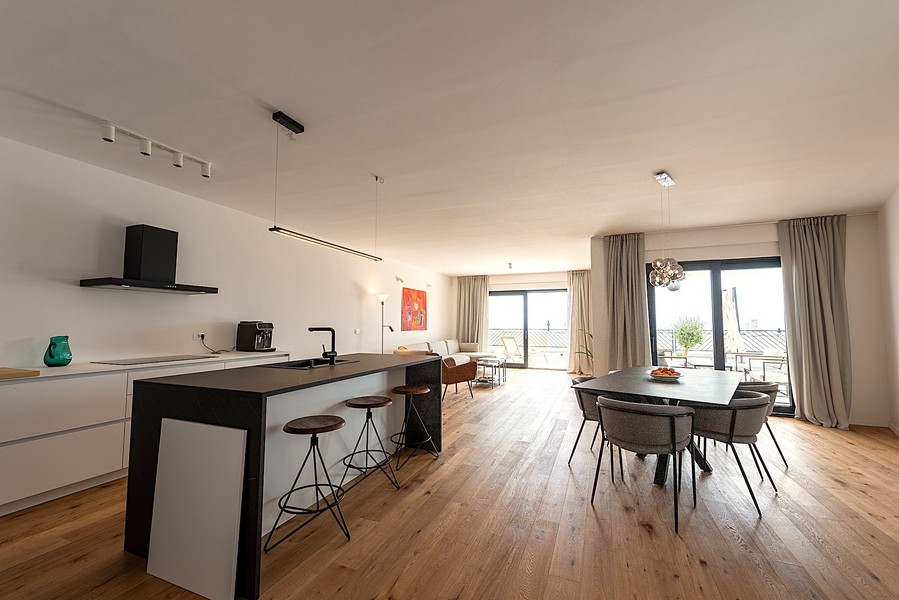 Nowoczesna kuchnia z wyspą, jadalnią i salonem w tle