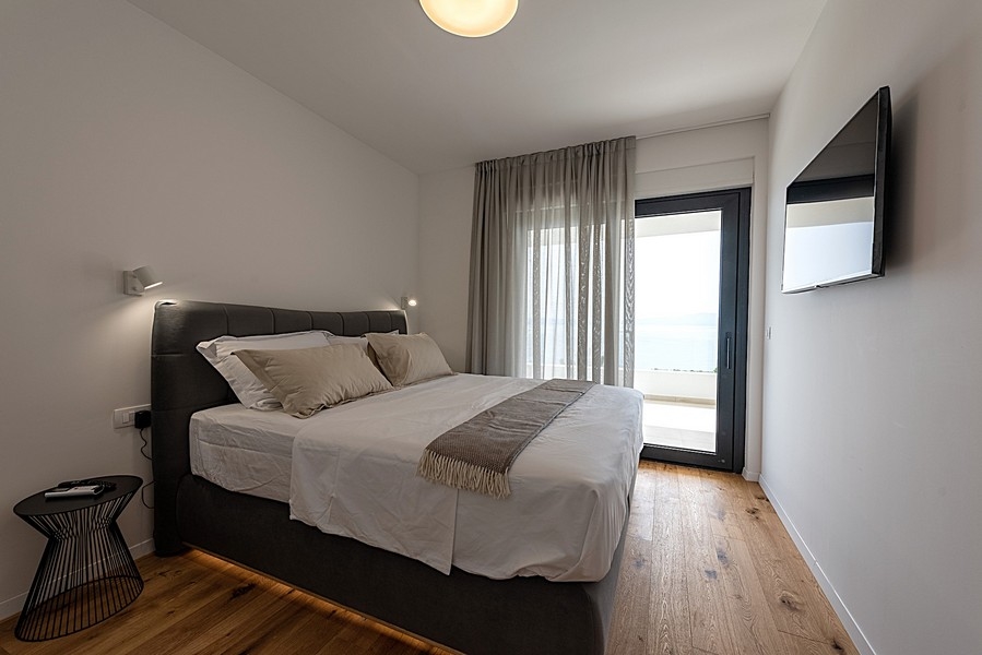 Sypialnia z podwójnym łóżkiem, dostępem do balkonu i widokiem na morze