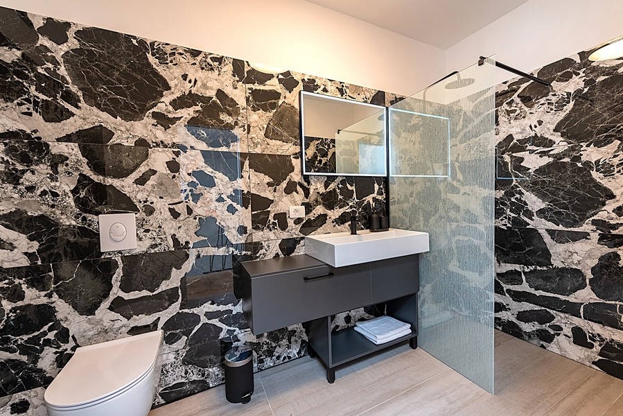 Nowoczesna łazienka z czarną marmurową ścianą i kabiną prysznicową