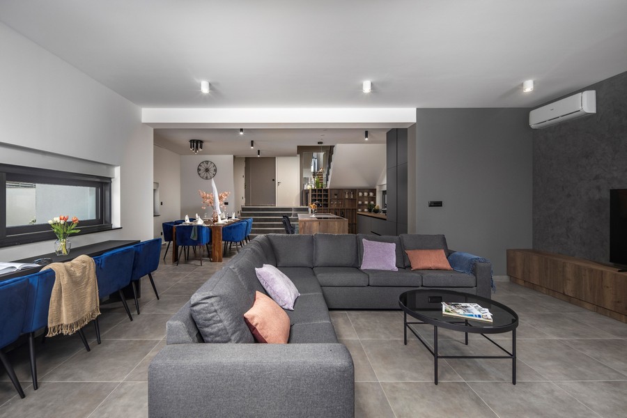 Nowoczesny salon z szarą sofą i jadalnią