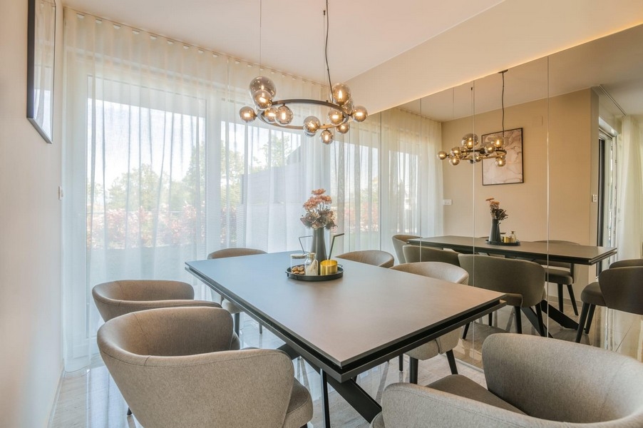 Przytulna jadalnia z tapicerowanymi krzesłami i designerskimi lampami