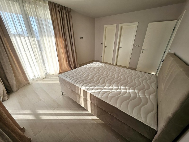 Przestronna sypialnia z dużymi oknami i podwójnym łóżkiem