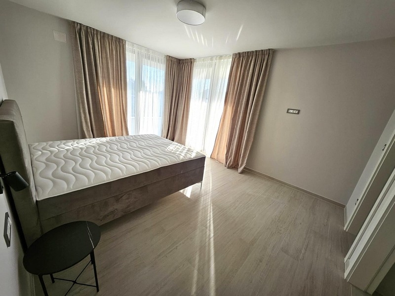 Jasna sypialnia z podwójnym łóżkiem, zasłonami i drzwiami balkonowymi