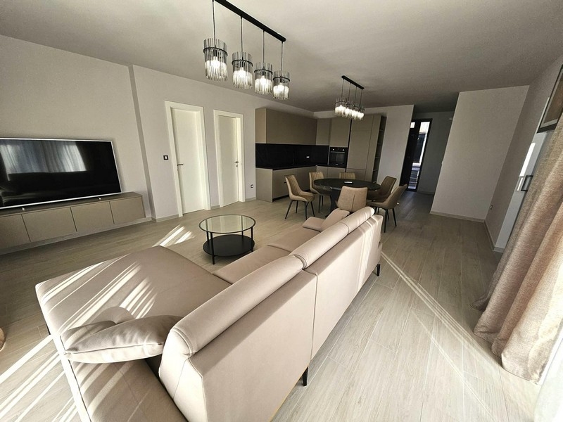 Otwarta część dzienna z sofą, telewizorem i designerskimi lampami