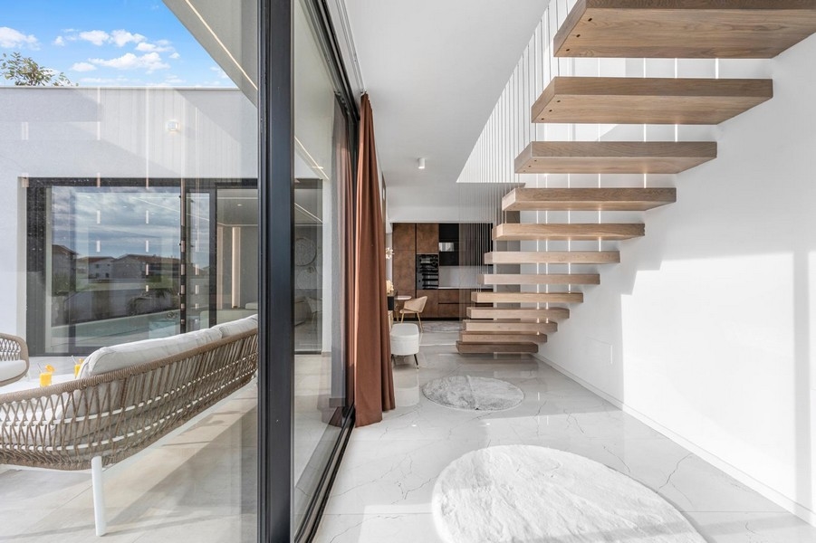 Jasna galeria z pływającymi schodami i dużymi oknami