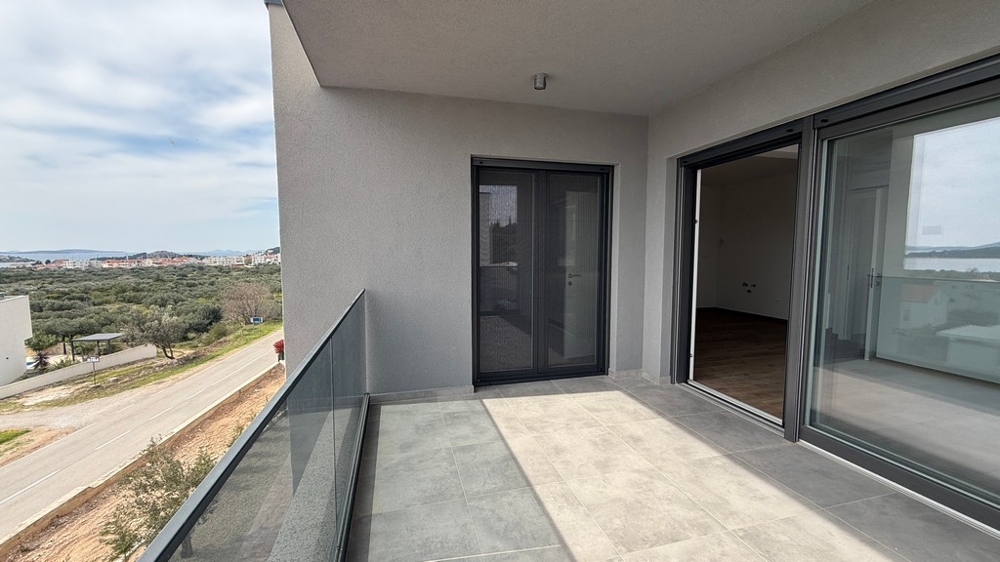 Zadaszony balkon ze szklanymi balustradami i dostępem do części dziennej