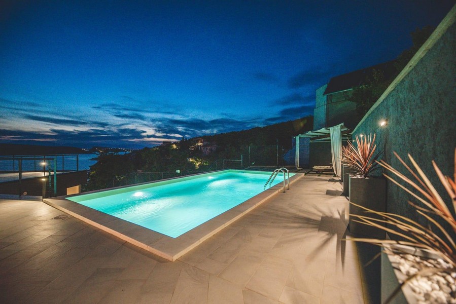 Taras przy basenie z widokiem na morze w nocy