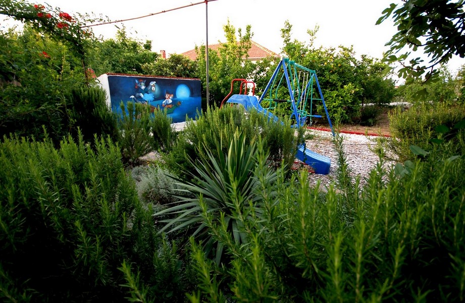 Plac zabaw dla dzieci w ogrodzie z dużą ilością zieleni