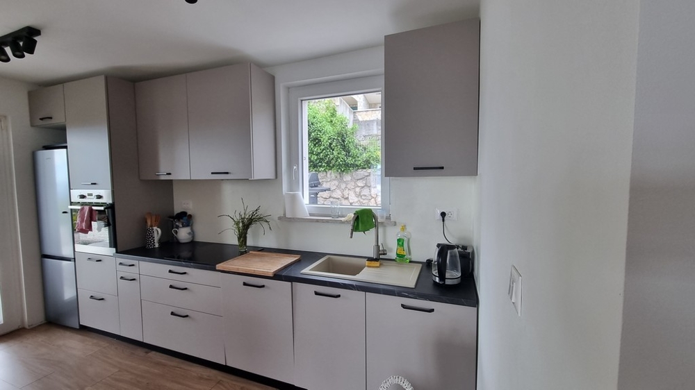 Nowocześnie wyposażona kuchnia z oknem i widokiem na ogród