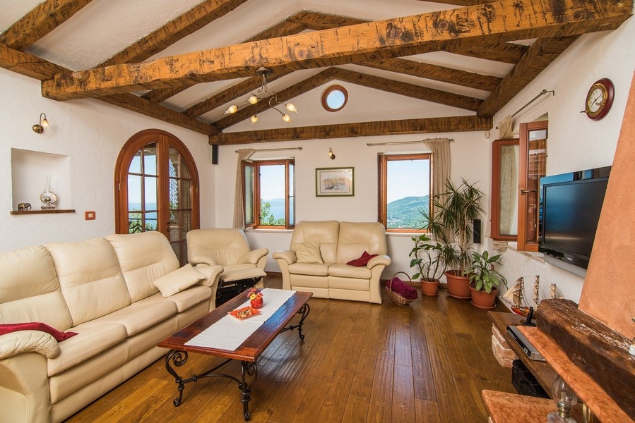 Pokój dzienny z drewnianymi belkami i widokiem na zieleń