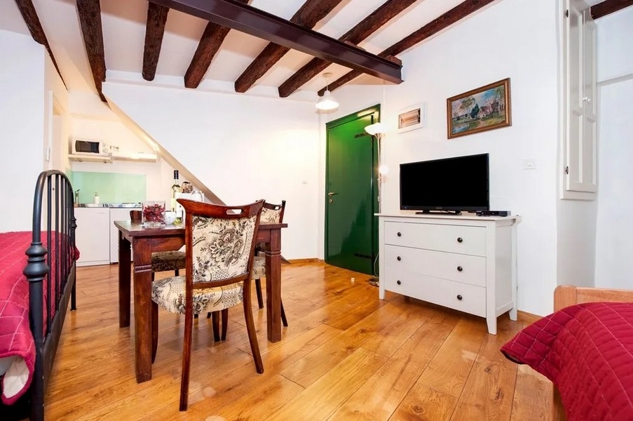 Studio z drewnianą podłogą, telewizorem i otwartą kuchnią