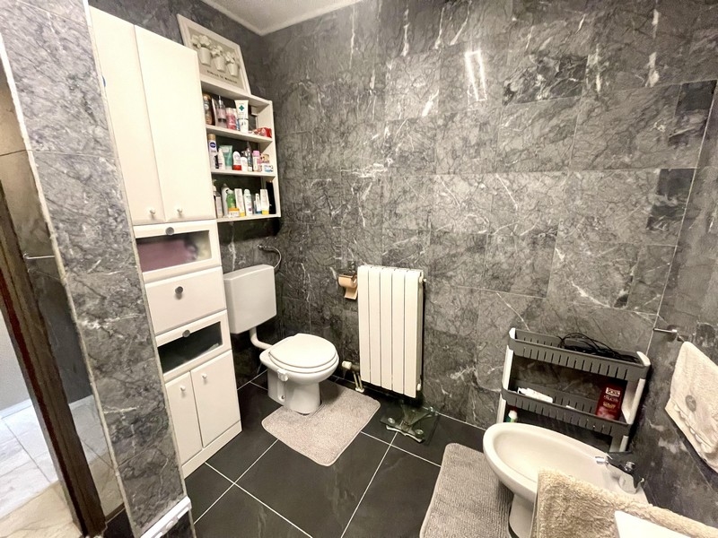 Łazienka z toaletą, bidetem i szarymi płytkami ściennymi