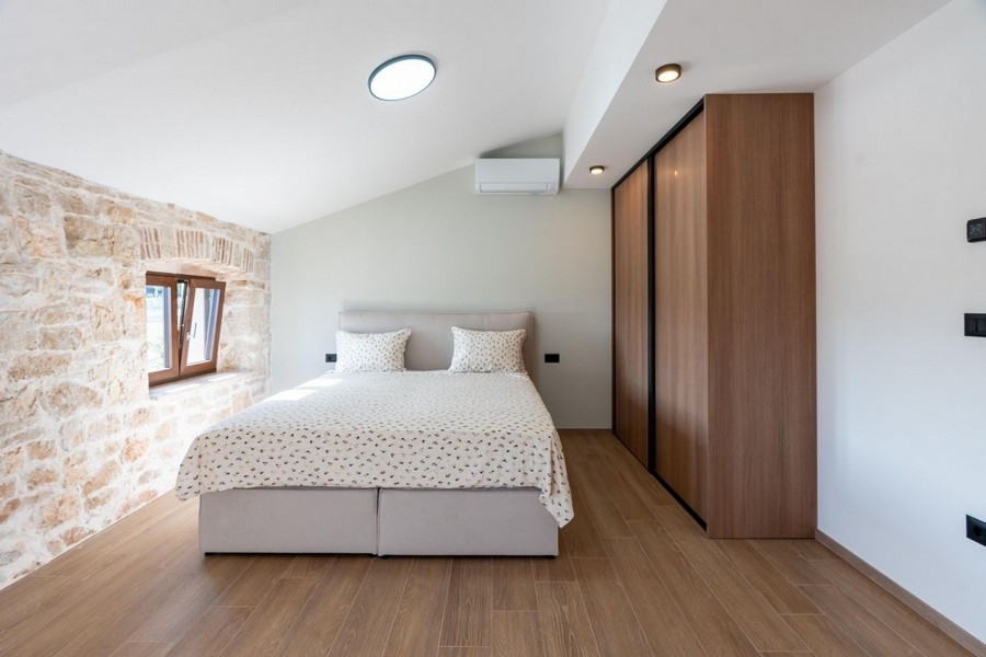 Jasna sypialnia z naturalną kamienną ścianą