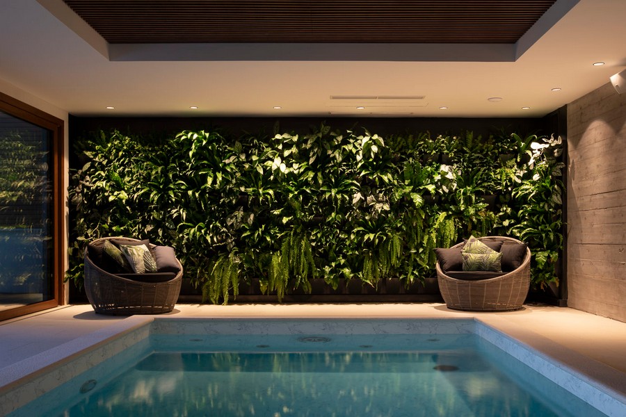 Kryty basen ze ścianą z zielonych roślin i częścią wypoczynkową