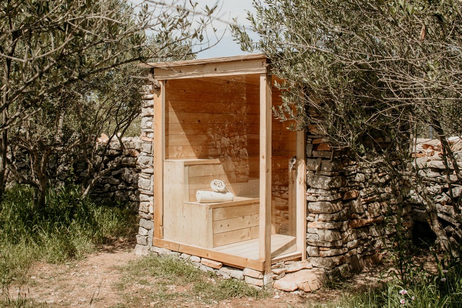 Sauna zewnętrzna w ogrodzie z kamieniem naturalnym i boazerią
