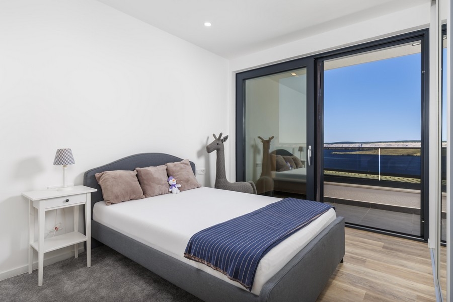 Jasna sypialnia z wyjściem na balkon i widokiem na morze
