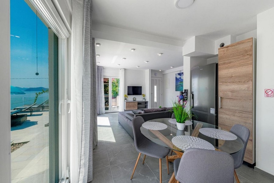 Jadalnia ze szklanym stołem i wyjściem na taras z widokiem na morze