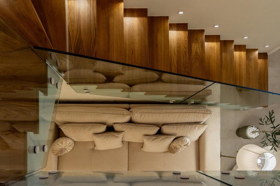 Widok na klatkę schodową z drewnianymi stopniami i szklanymi balustradami