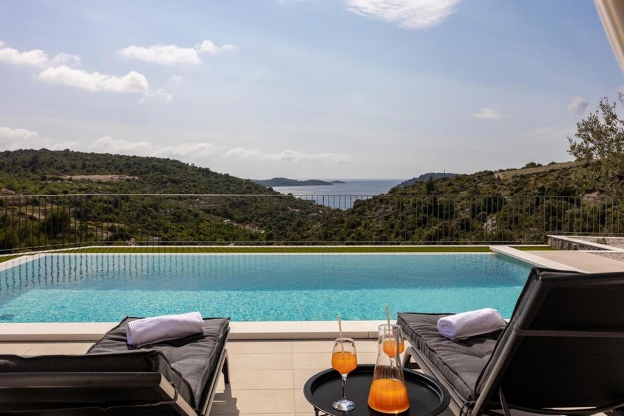 Basen typu infinity z widokiem na morze i leżakami