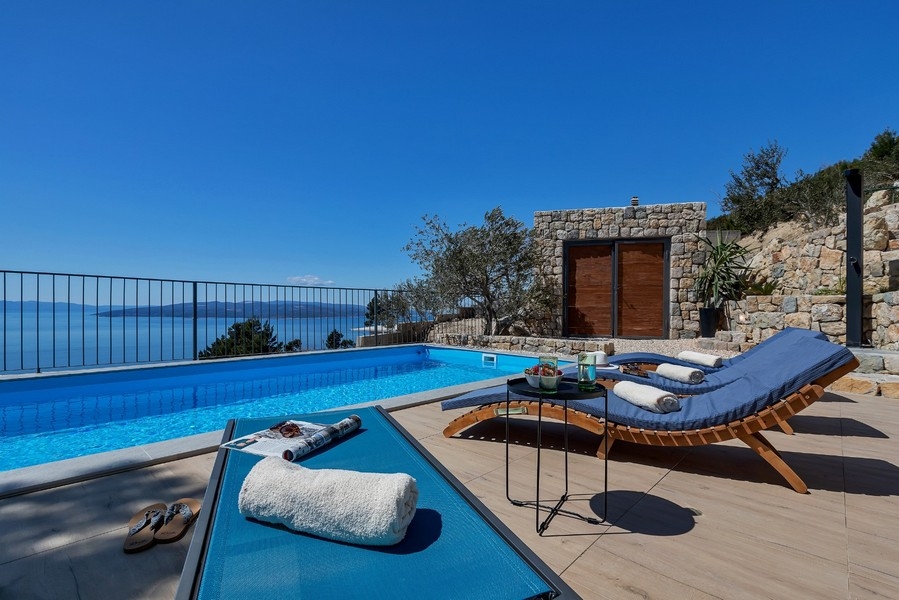 Basen z leżakami i widokiem na morze